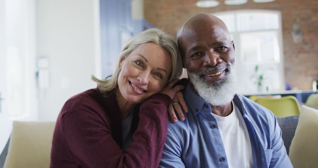 Portrait of happy senior diverse couple in living room sitting on sofa, embracing and smiling - Free Images, Stock Photos and Pictures on Pikwizard.com