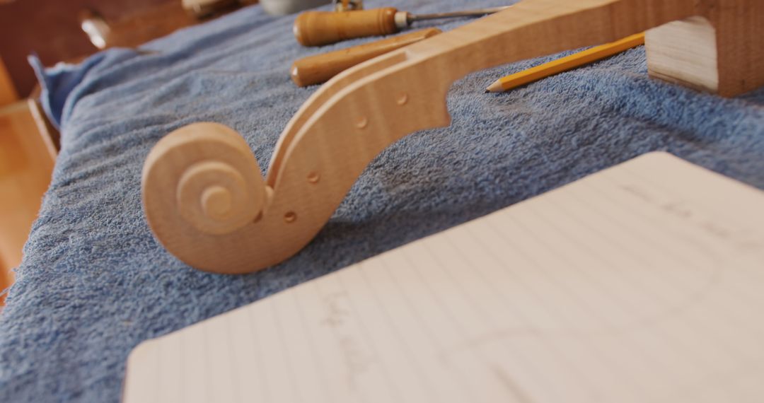 Handcrafted Wooden Violin Scroll on Workbench with Draft Sketch - Free Images, Stock Photos and Pictures on Pikwizard.com