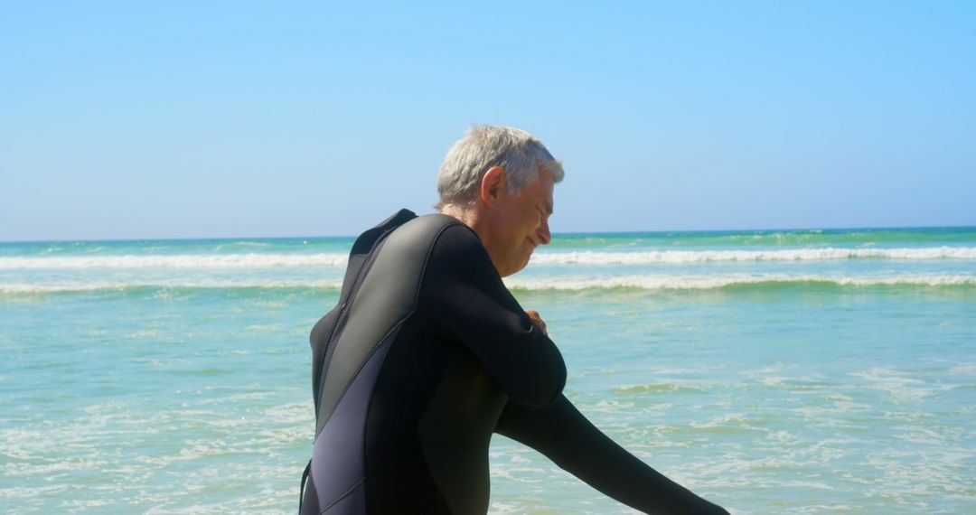 Senior Surfer Preparing on Sunlit Beach in Wetsuit