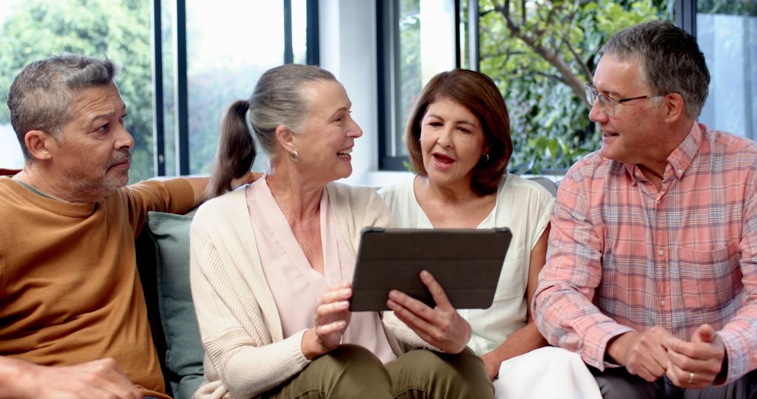 Diverse Senior Friends Discussing Over Tablet at Home