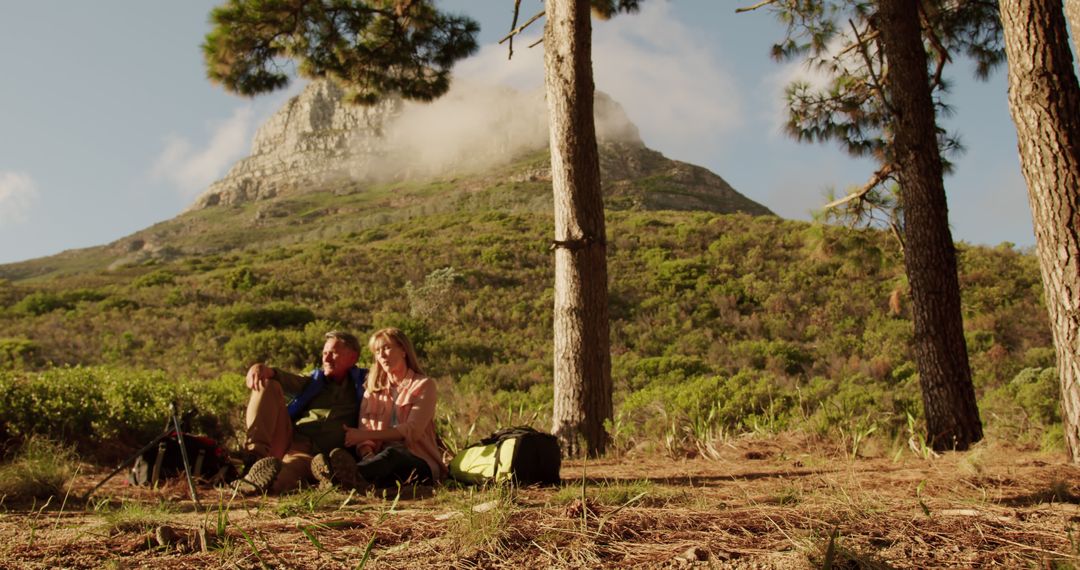 Couple Relaxing Under Trees with Mountain View in Background - Free Images, Stock Photos and Pictures on Pikwizard.com