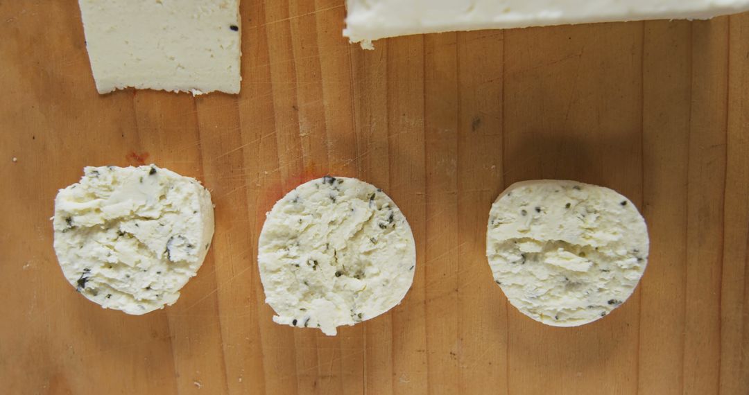 Fresh Slices of Herb-Infused Cheese on Wooden Board - Free Images, Stock Photos and Pictures on Pikwizard.com