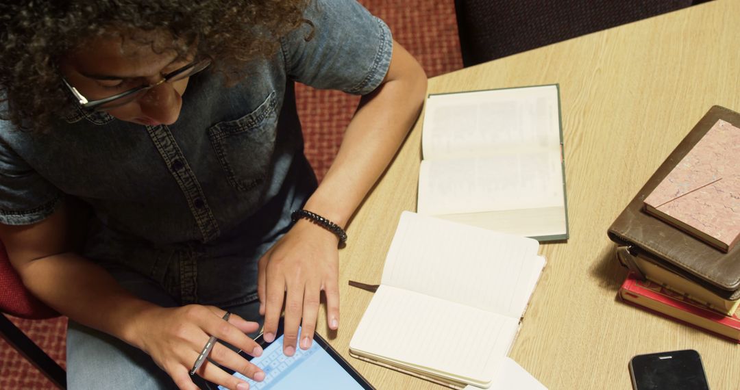 Student studying with digital tablet and open books on desk - Free Images, Stock Photos and Pictures on Pikwizard.com