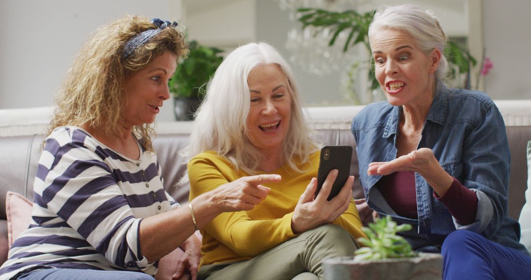 Joyful Senior Women Using Smartphone Indoors Sharing a Lively Moment - Free Images, Stock Photos and Pictures on Pikwizard.com