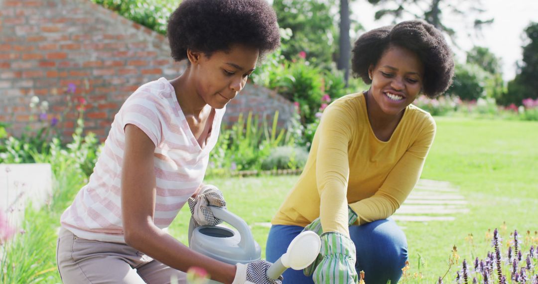 Afro-American Women Watering Plants and Smiling in Garden - Free Images, Stock Photos and Pictures on Pikwizard.com