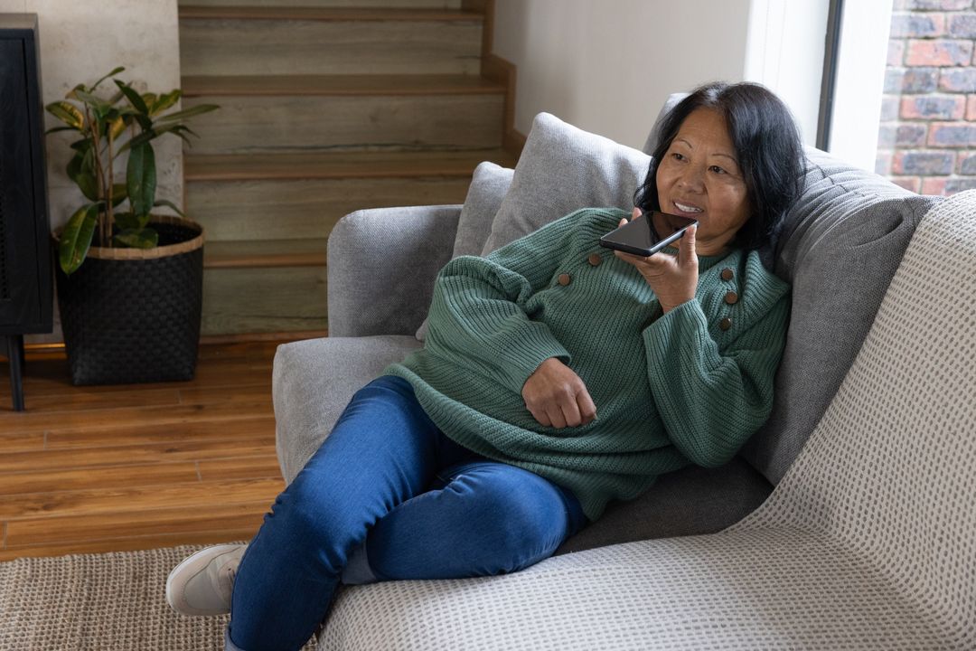 Senior Woman Relaxing on Sofa Using Smartphone for Communication