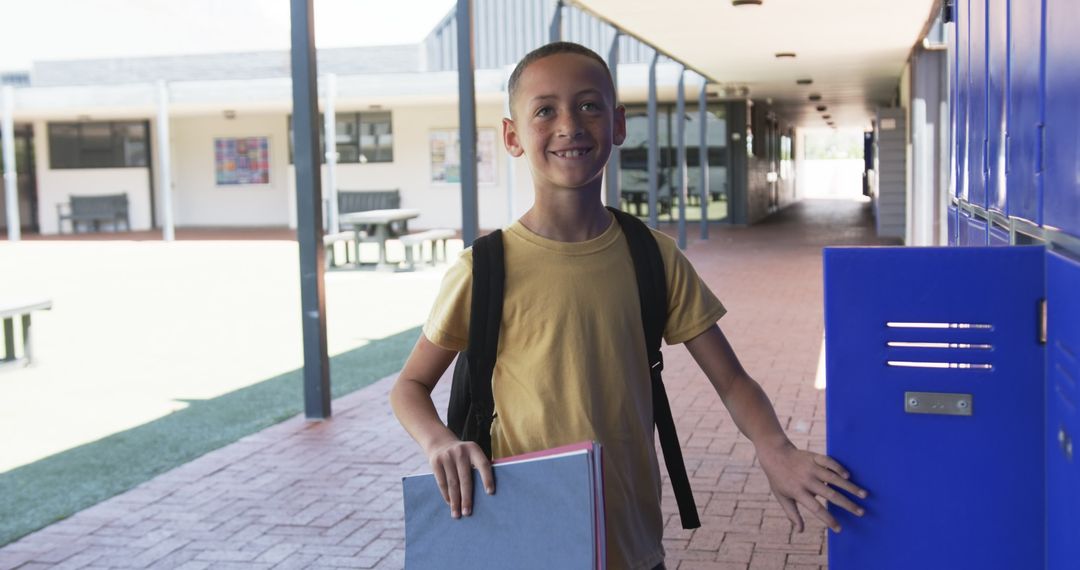 Smiling Boy in School Hallway Holding Textbooks