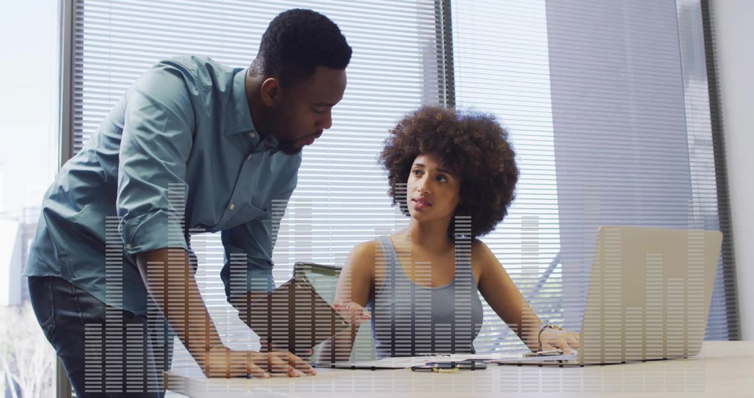 Collaborating over data visualization at bright office desk with laptop and printed reports