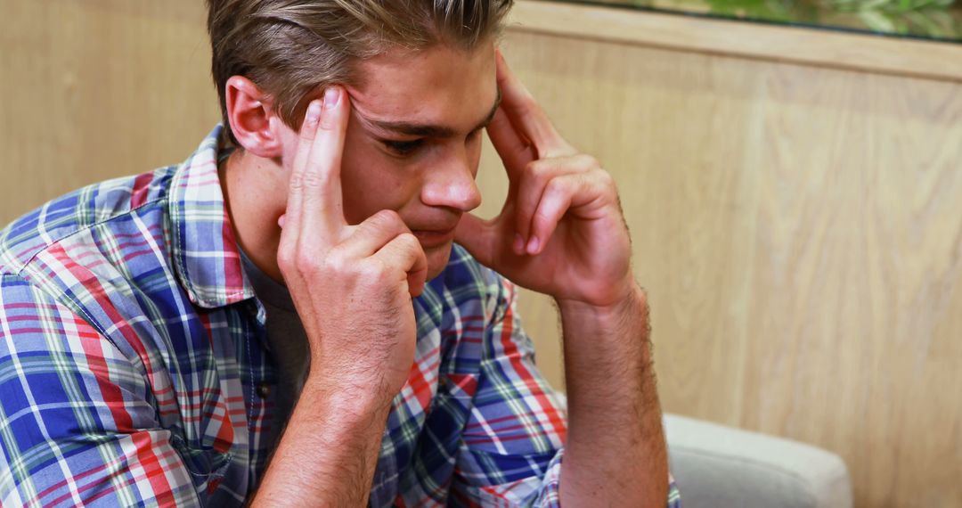 Stressed Young Man Holding Head, Contemplating Solutions - Free Images, Stock Photos and Pictures on Pikwizard.com