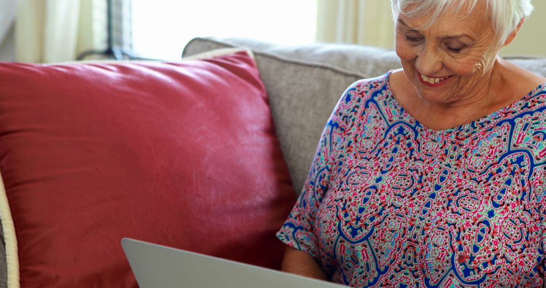 Smiling Senior Woman Using Laptop on Cozy Couch at Home - Free Images, Stock Photos and Pictures on Pikwizard.com