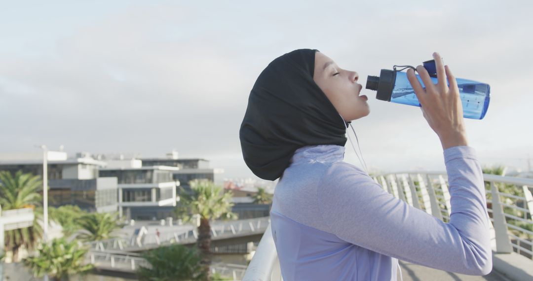 Active Woman Hydrating After Outdoor Workout in Hijab - Free Images, Stock Photos and Pictures on Pikwizard.com