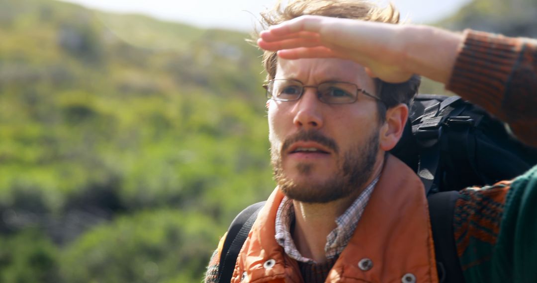 Man Hiking on Mountain Shielding Eyes Admiring Scenic View
