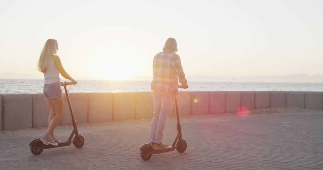 Young Couple Riding Electric Scooters by the Beach at Sunset - Free Images, Stock Photos and Pictures on Pikwizard.com