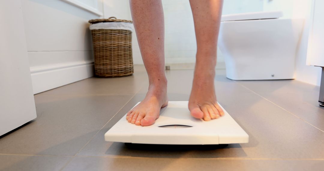 Person Weighing Themselves on Scale in Modern Bathroom - Free Images, Stock Photos and Pictures on Pikwizard.com