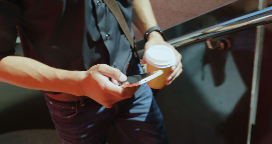 Man texting and holding coffee cup in urban setting - Free Images, Stock Photos and Pictures on Pikwizard.com