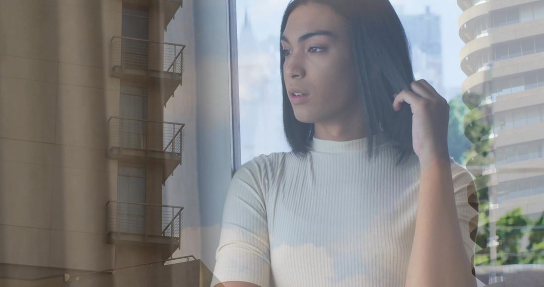 Urban reflection portrait of man in ribbed top looking out through glass window