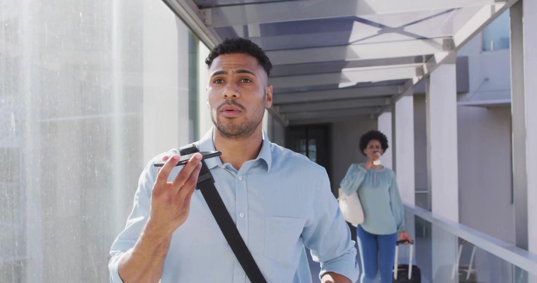 Hispanic Man Using Smartphone in Modern Skybridge
