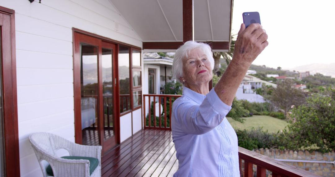 Senior Woman Taking Selfie on Balcony in Scenic Setting