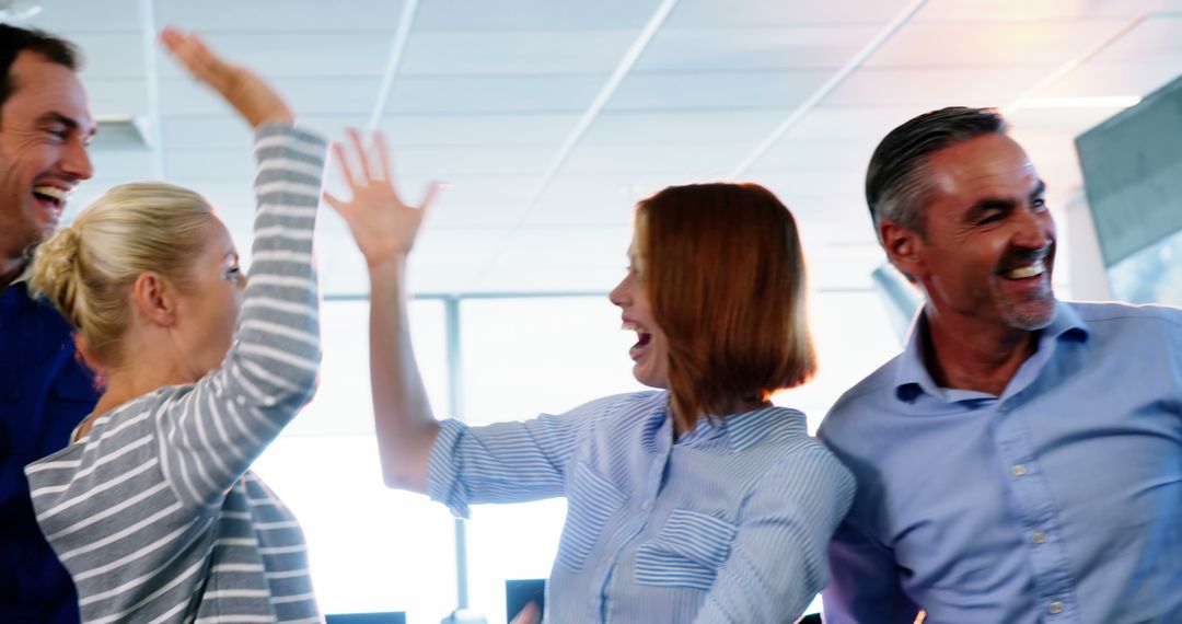 Team Celebrating Success with High Fives in Modern Office - Free Images, Stock Photos and Pictures on Pikwizard.com