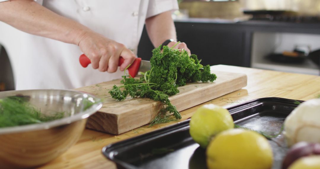 Chef Chopping Fresh Parsley on Wooden Cutting Board in Kitchen - Free Images, Stock Photos and Pictures on Pikwizard.com