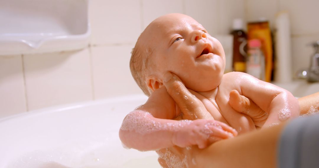 Smiling Infant Enjoying Bath Time Holding by Parent's Hands - Free Images, Stock Photos and Pictures on Pikwizard.com