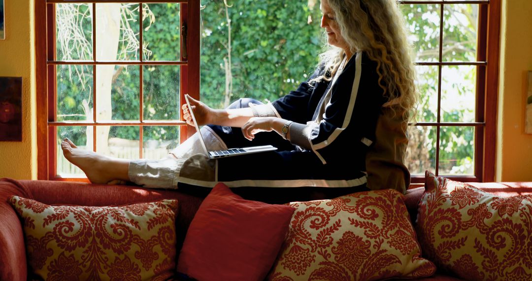 Woman Relaxing on Couch by Window Using Laptop - Free Images, Stock Photos and Pictures on Pikwizard.com