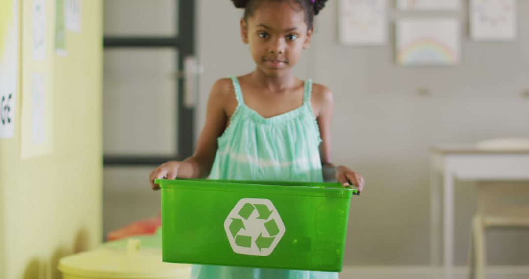 Image of happy african american girl holding box with recycling symbol in classroom - Free Images, Stock Photos and Pictures on Pikwizard.com