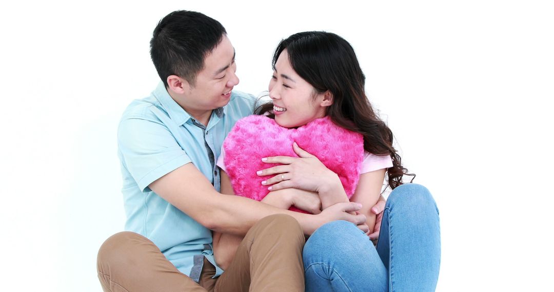 Happy Couple Embracing with Pink Heart Pillow on White Background - Free Images, Stock Photos and Pictures on Pikwizard.com