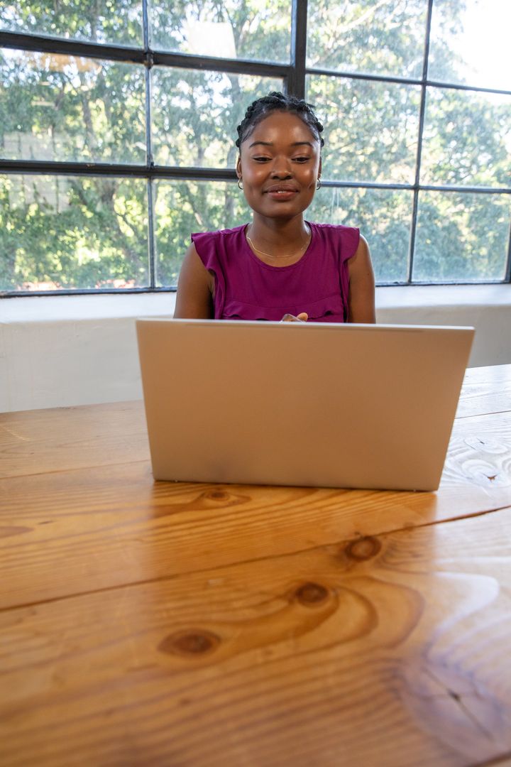 Woman Typing on Laptop in Sunlit Workspace