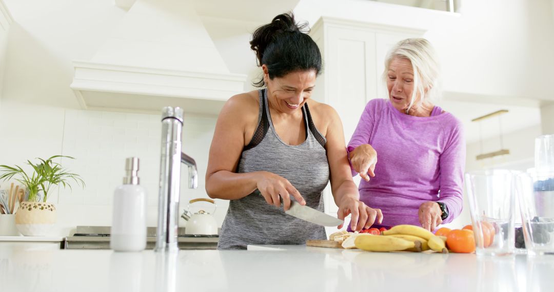 Two Women Smiling and Cooking Together in Modern Kitchen - Free Images, Stock Photos and Pictures on Pikwizard.com