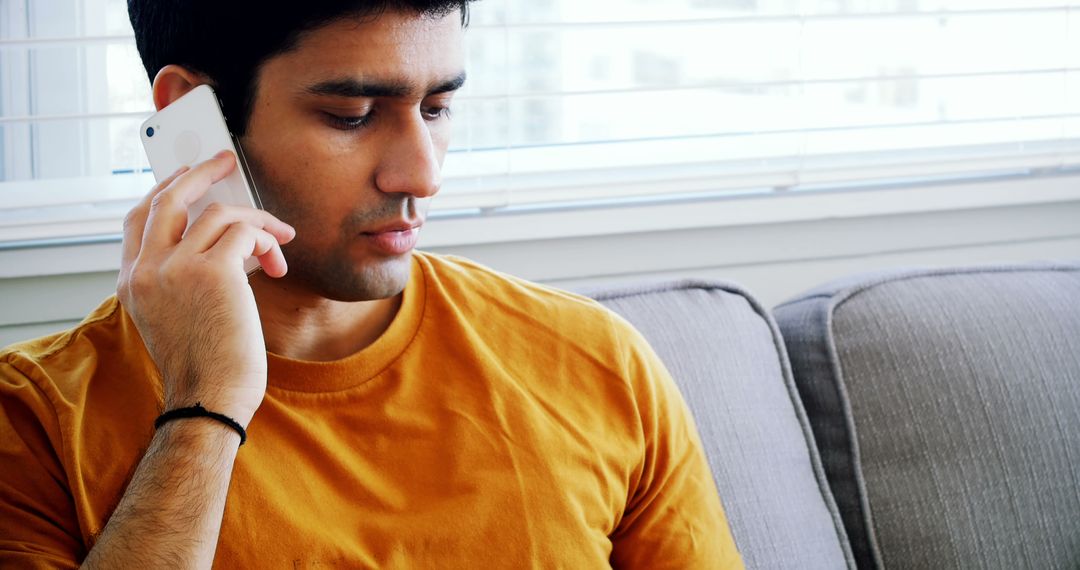 Young Man Concentrating During Phone Call in Bright Room - Free Images, Stock Photos and Pictures on Pikwizard.com