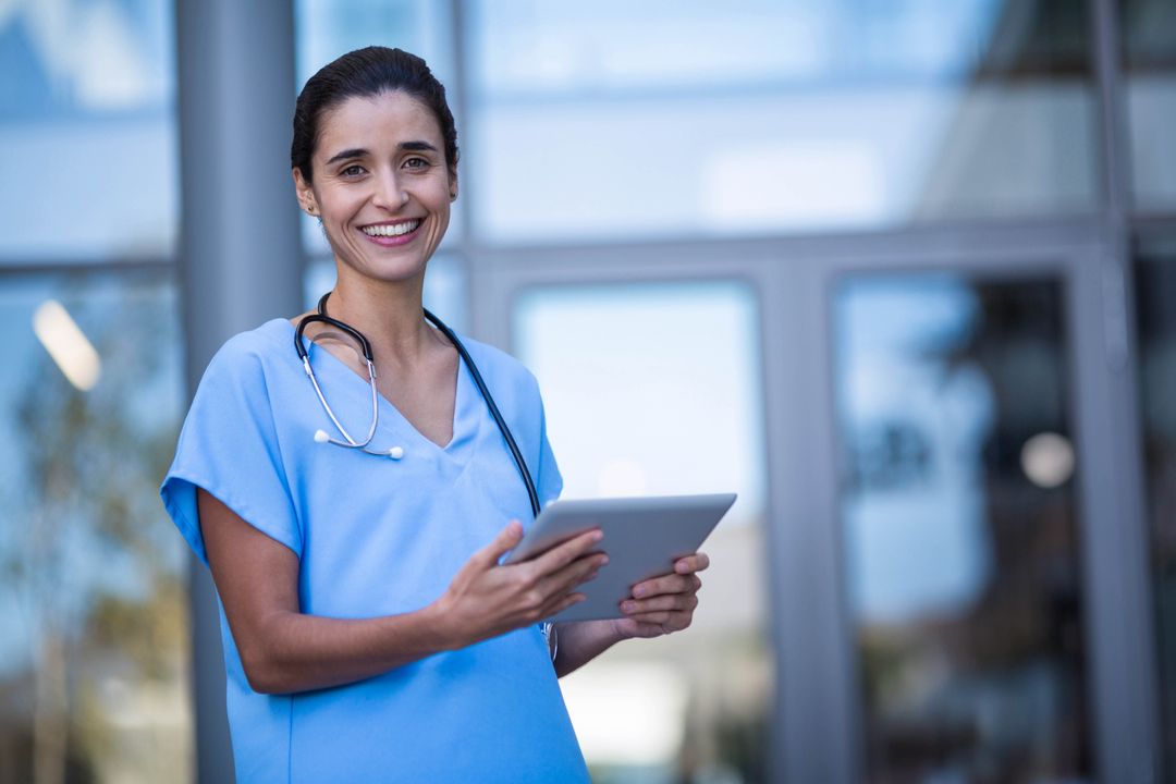 Female Healthcare Worker Smiling Outdoors Using Tablet