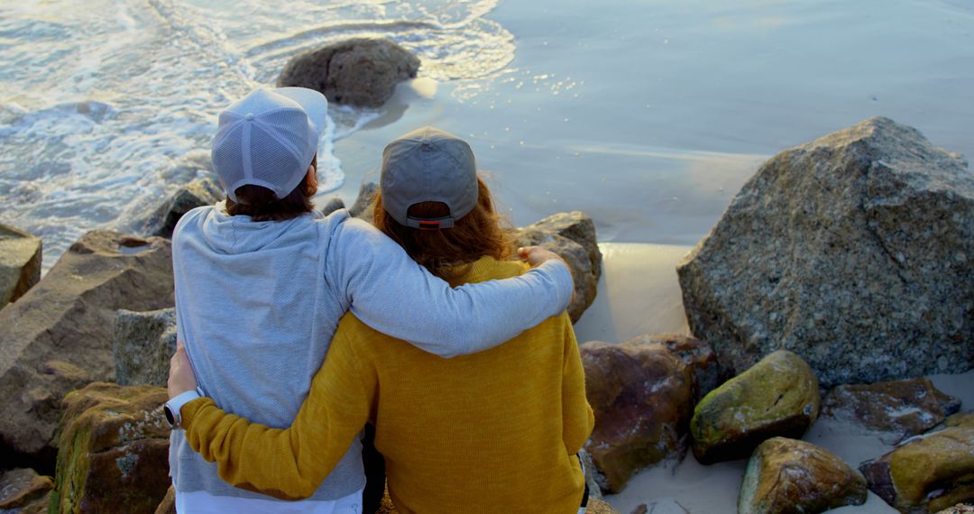 Couple Embracing on Rocky Beach Watching Waves - Free Images, Stock Photos and Pictures on Pikwizard.com