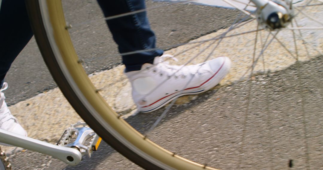 Closeup of person wearing sneakers stepping near bicycle wheel - Free Images, Stock Photos and Pictures on Pikwizard.com