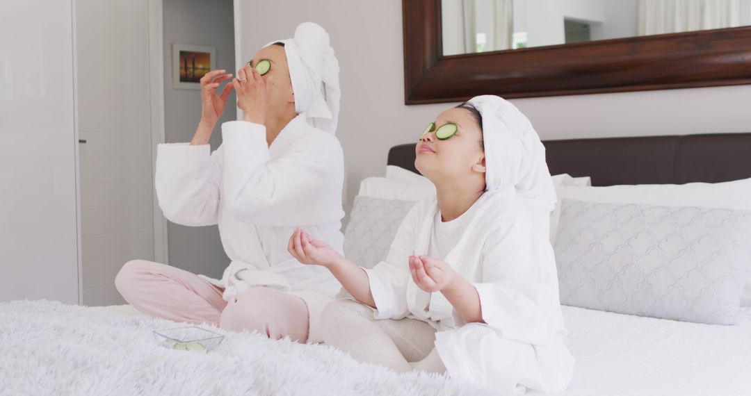 Image of happy asian mother and daughter in robes doing cucumber mask and resting - Free Images, Stock Photos and Pictures on Pikwizard.com