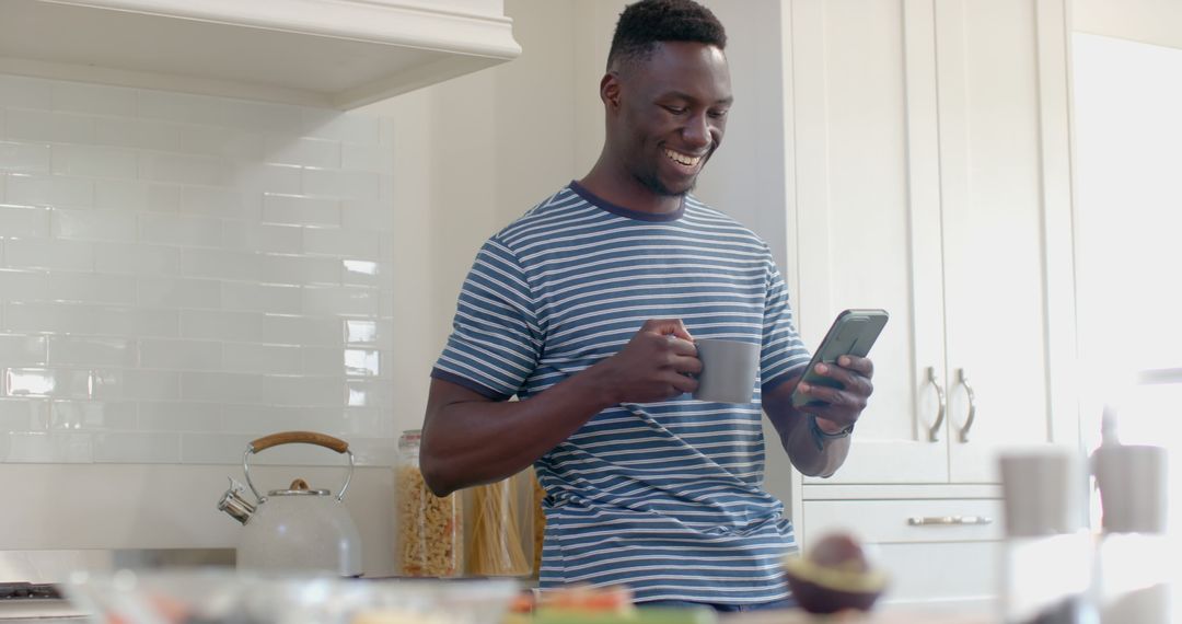 Happy Man Drinking Coffee While Using Smartphone in Modern Kitchen - Free Images, Stock Photos and Pictures on Pikwizard.com