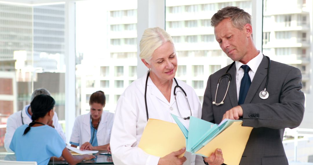 Experienced Medical Team Discussing Patient Records in Modern Clinic - Free Images, Stock Photos and Pictures on Pikwizard.com