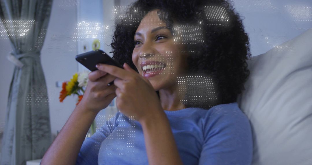 Smiling woman using smartphone while reclining on couch for cozy home relaxation