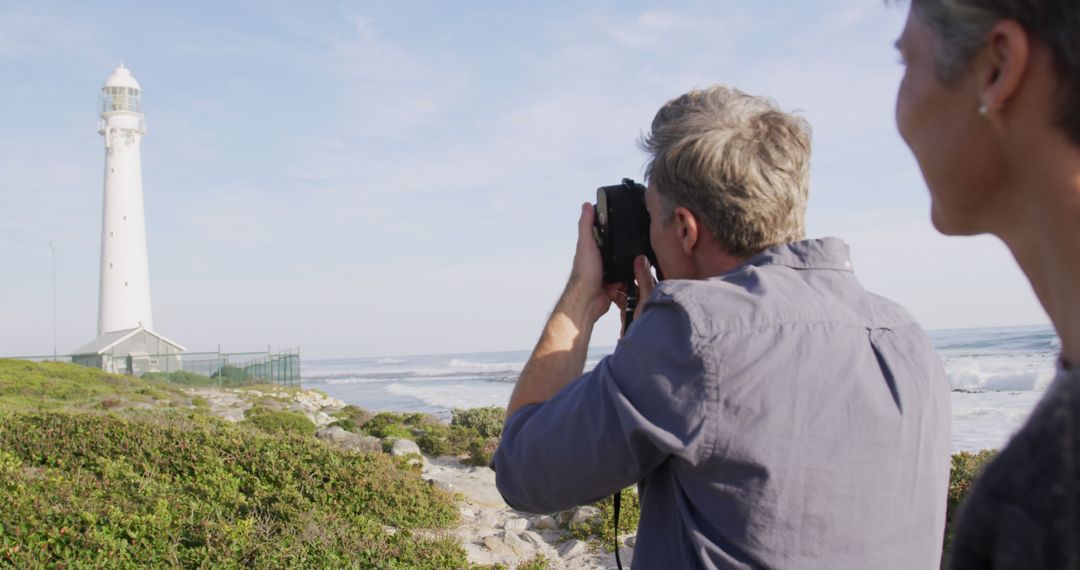 Senior Couple Photographing Beach Lighthouse on Sunny Day - Free Images, Stock Photos and Pictures on Pikwizard.com