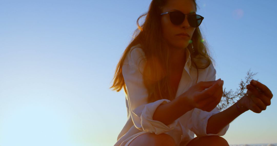 Woman in Sunglasses Holding Plant Twig in Sunset - Free Images, Stock Photos and Pictures on Pikwizard.com