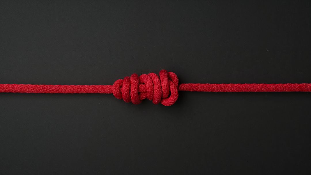 Intricately Tied Red Rope Knot on Black Background