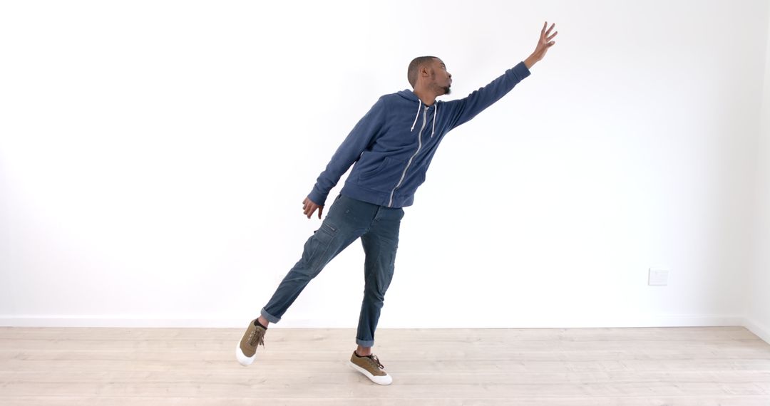 Young Man Stretching Arm Balancing on One Leg Indoors