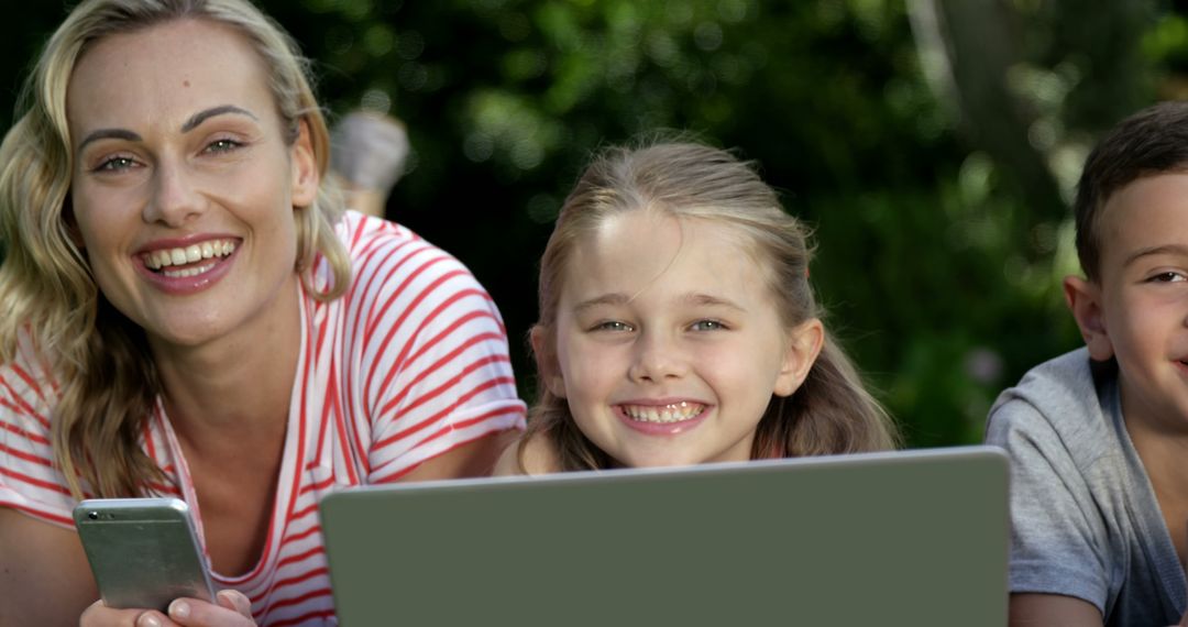 Mother and Children Relaxing Outdoors with Laptop and Smartphone Smiling - Free Images, Stock Photos and Pictures on Pikwizard.com