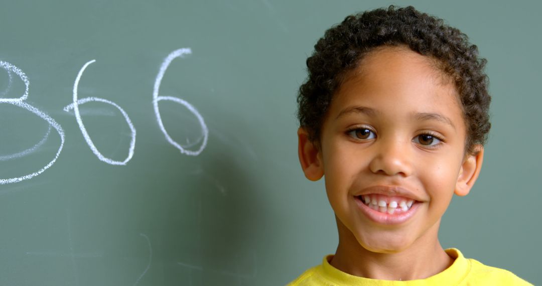 Laughing Schoolboy Standing by Chalkboard in Classroom
