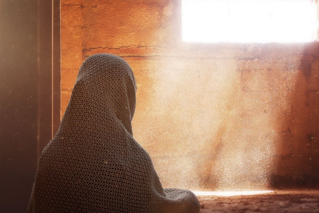 Person Sitting in Dusty Sunlit Room Wrapped in Shawl - Free Images, Stock Photos and Pictures on Pikwizard.com