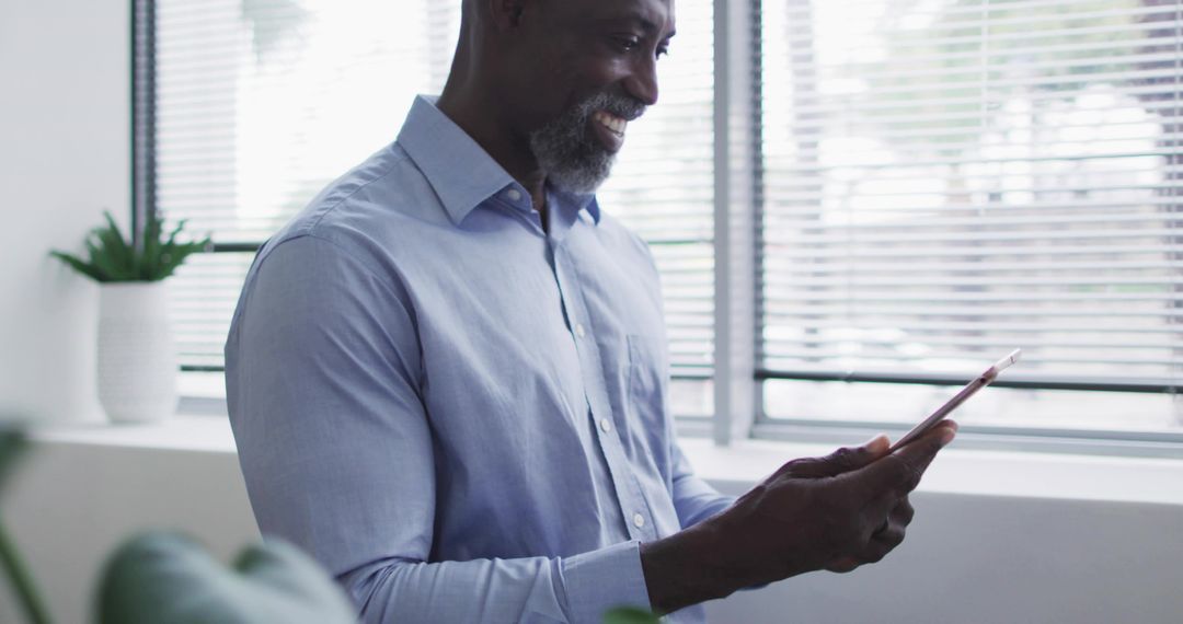 Professional Smiling Man Using Tablet by Office Window