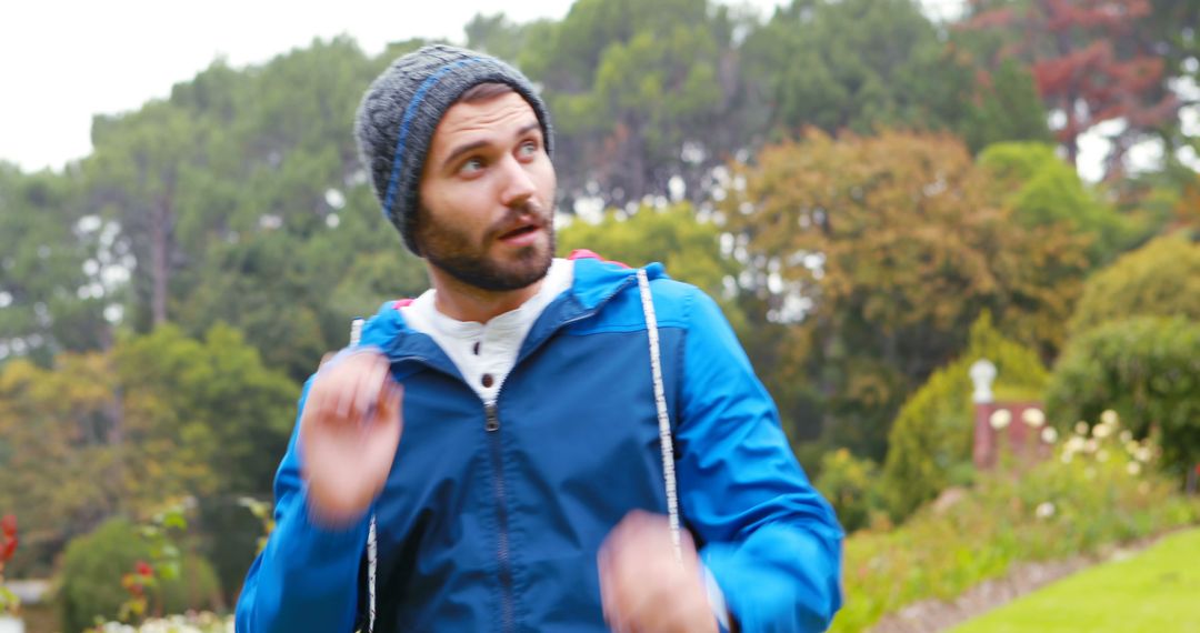 Surprised man in blue jacket and knitted beanie in lush park - Free Images, Stock Photos and Pictures on Pikwizard.com