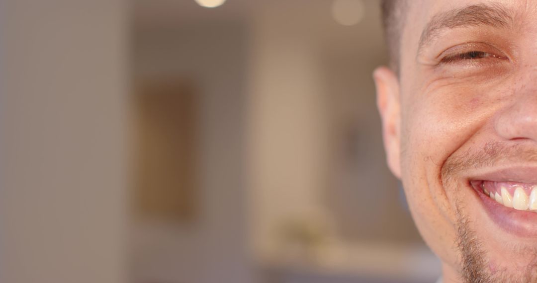 Smiling man presenting warm half-face close-up with cozy interior bokeh and copy space