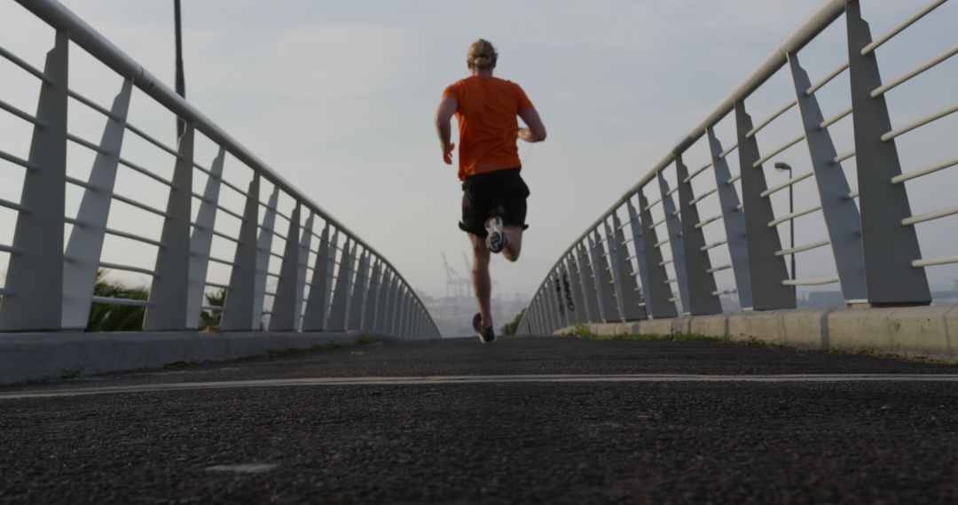 Rear View of Man Running on Urban Bridge during Morning Exercise - Free Images, Stock Photos and Pictures on Pikwizard.com