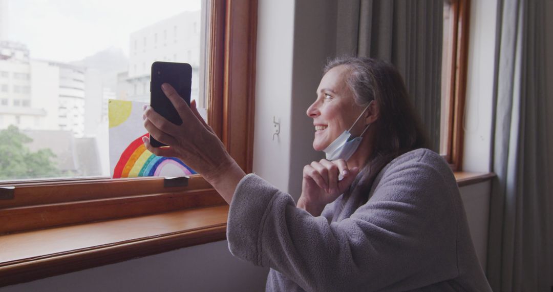 Smiling Senior Woman Facetiming by Window with Rainbow Painting - Free Images, Stock Photos and Pictures on Pikwizard.com